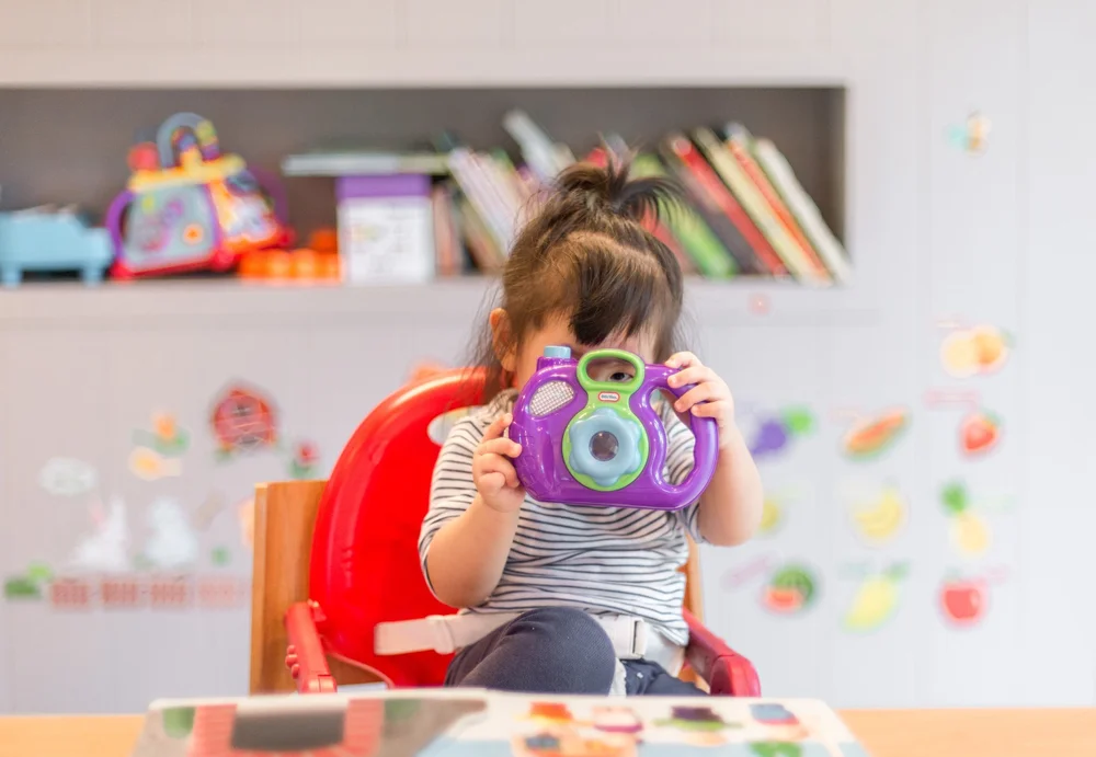 A young child in a colorful therapy playroom playing with a toy camera